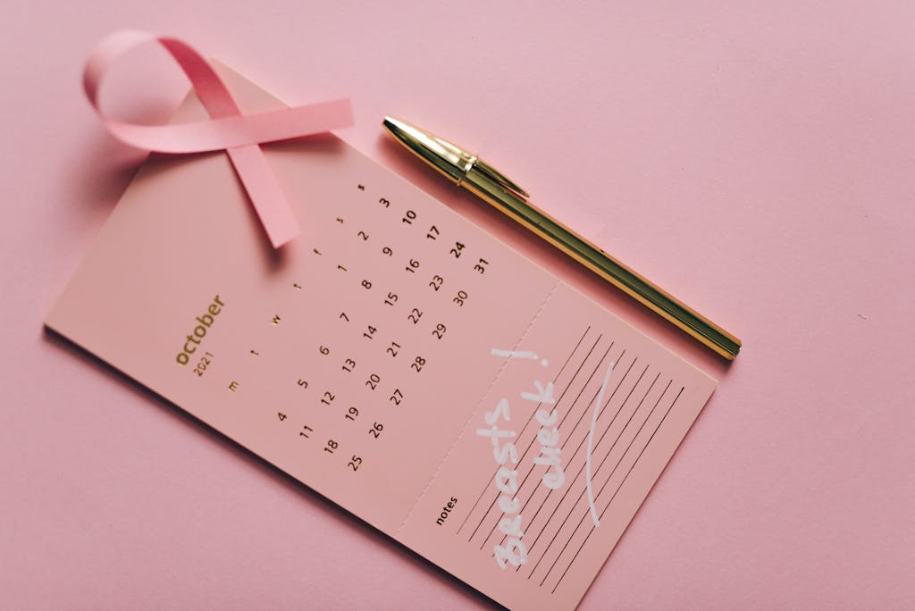 Pink calendar with ribbon and pen for Breast Cancer Awareness in October.