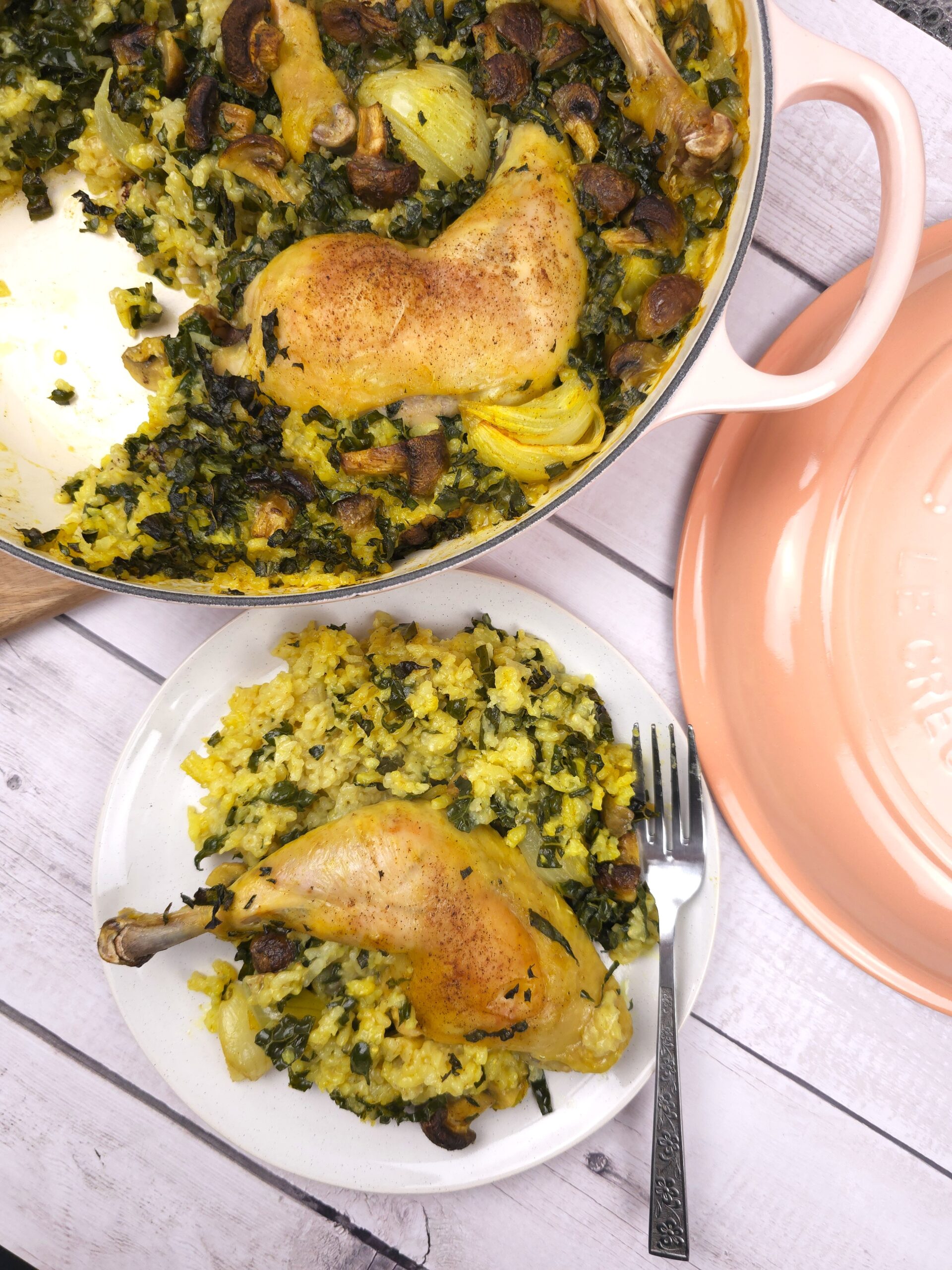 a plate with the cooked chicken, rice and kale, mushrooms next to a shallow cast iron baking casserole