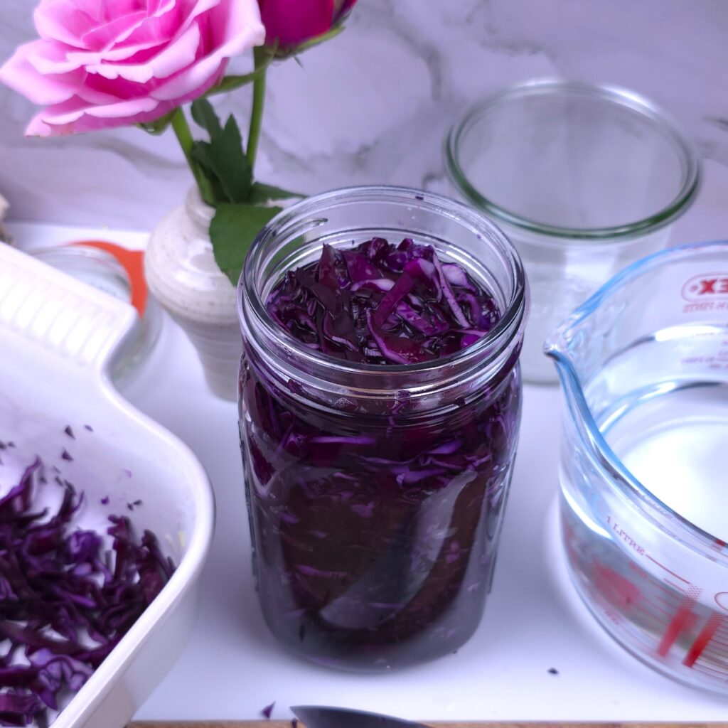 red cabbage shredded and placed in a jar with brine, ready for homemade sauerkraut fermentation
