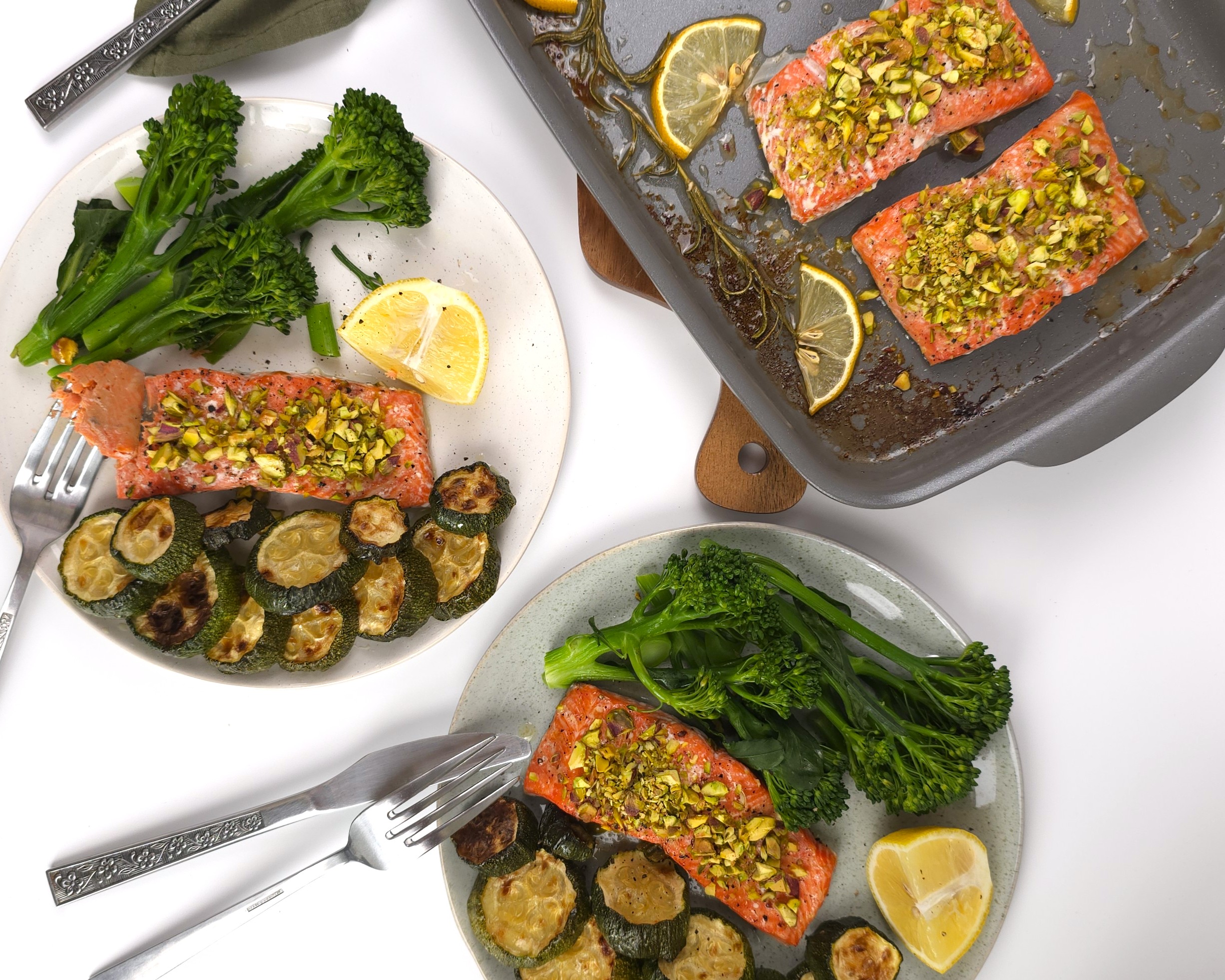 two plates with salmon portion and sides with roasted corgettes and tender steamed broccoli
