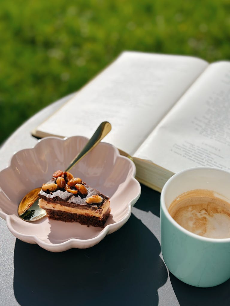 A serene outdoor setting with cake, coffee, and an open book writing a book reviews