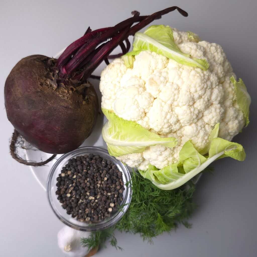 beetroot and cauliflower next to fresh dill, garlic and black pepper corns