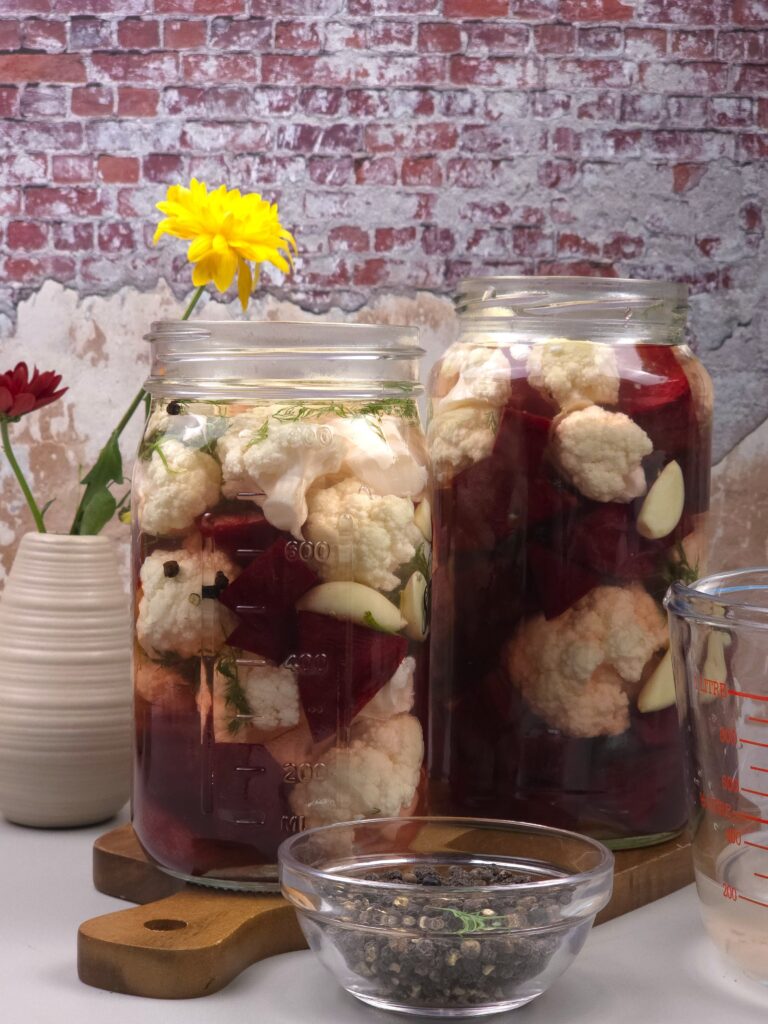 two jars with beets and cauliflower with salty brine