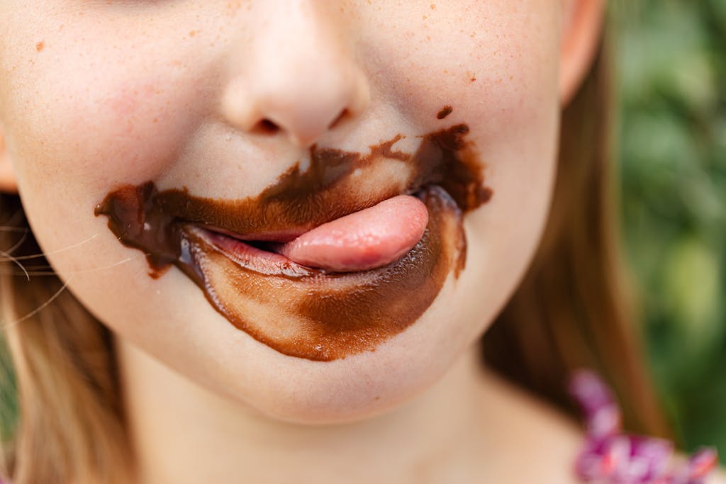 Close-up of a child licking chocolate with joy, showing enjoyment.
