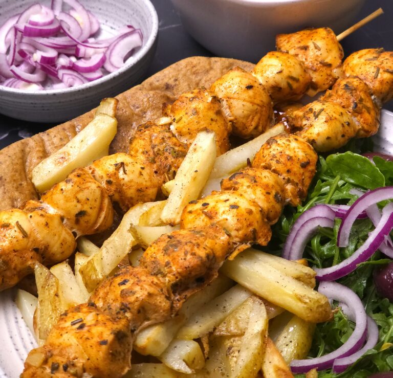 a closer look to greek chicken souvlaki in a plate along with sides