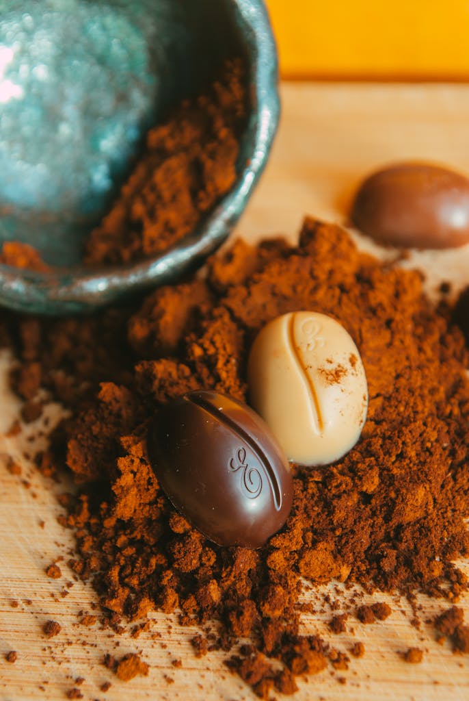 Close-up of assorted chocolates scattered in rich cocoa powder for a tempting treat.