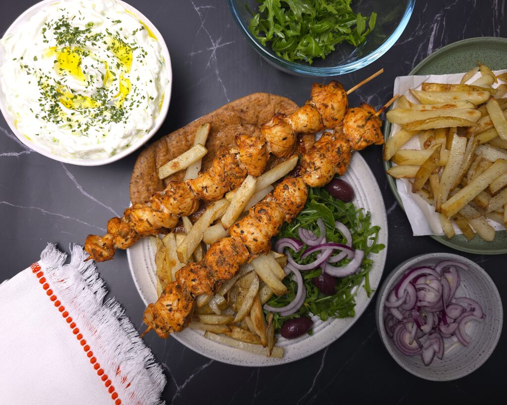 air fried Greek chicken souvlaki with tzatziki, oven-baked potato chips, fresh salad and red onion