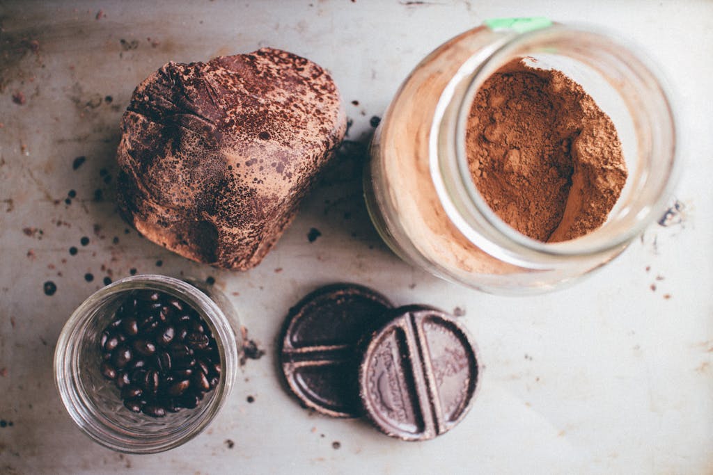 Top view of artisanal chocolate, cocoa powder, and coffee beans arranged in a rustic style.