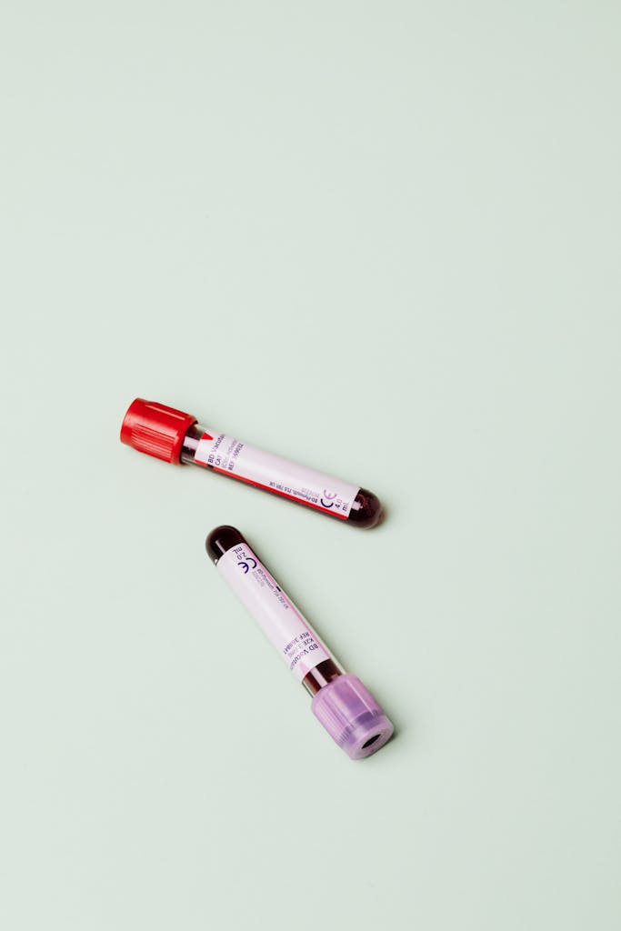 Two blood test tubes displayed on a pastel green background, ideal for medical themes.