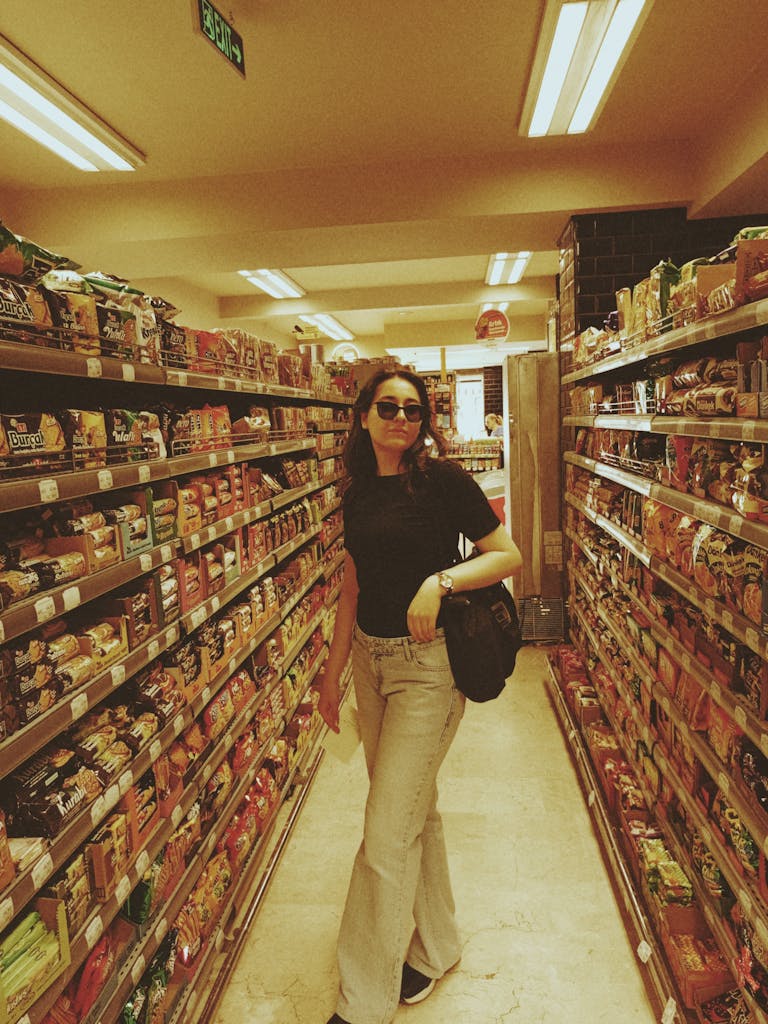 Woman browsing products in a supermarket aisle filled with various goods.