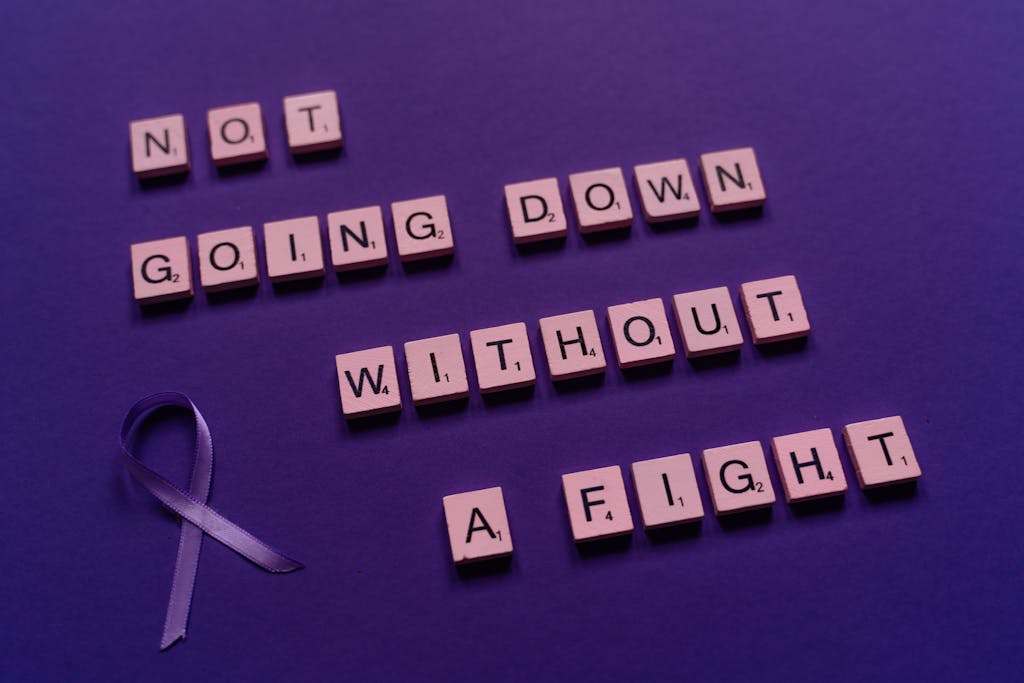 An inspirational quote made from Scrabble tiles alongside a purple awareness ribbon.