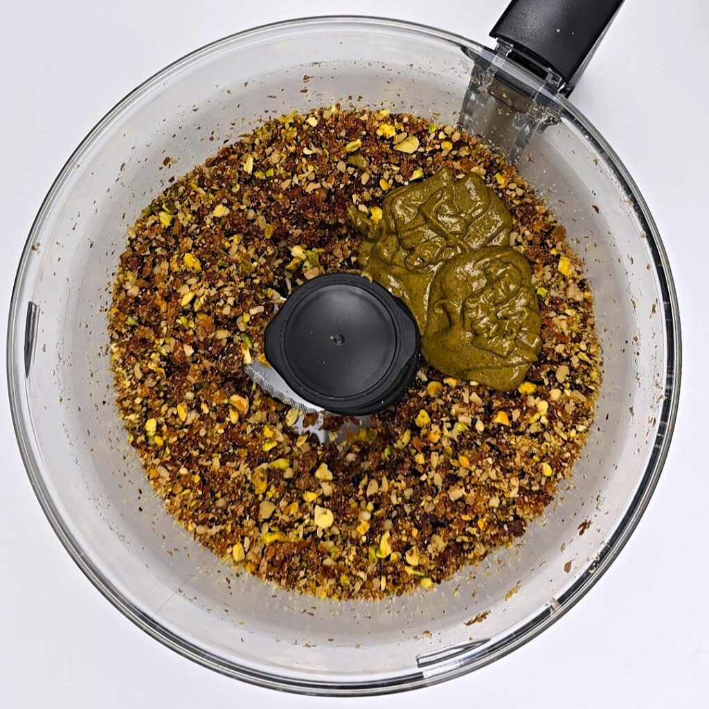 blended nuts and dates and pistachio butter in a food processor bowl