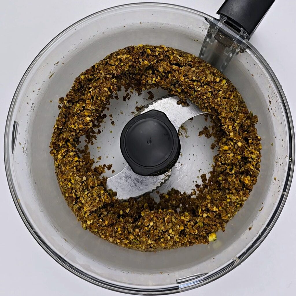 blended pistachio walnut and pistachio butter mixture in a food processor bowl