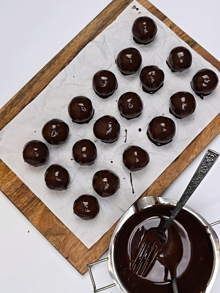coated energy balls with chocolate on wooden board