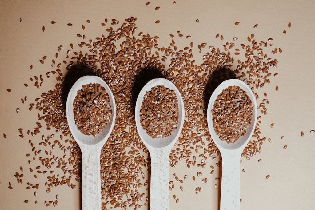Flat lay of organic flaxseeds, rich in Omega-3 fatty acids in wooden spoons showcasing natural nutrition and texture.