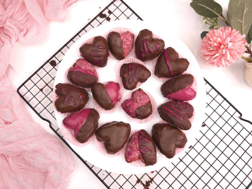 Heart-shaped chocolate raspberry valentines with pink decorations in a white plate