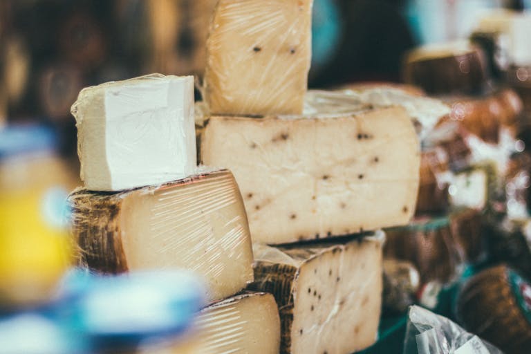 Close-up of various cheeses stacked indoors, showcasing variety and texture.
