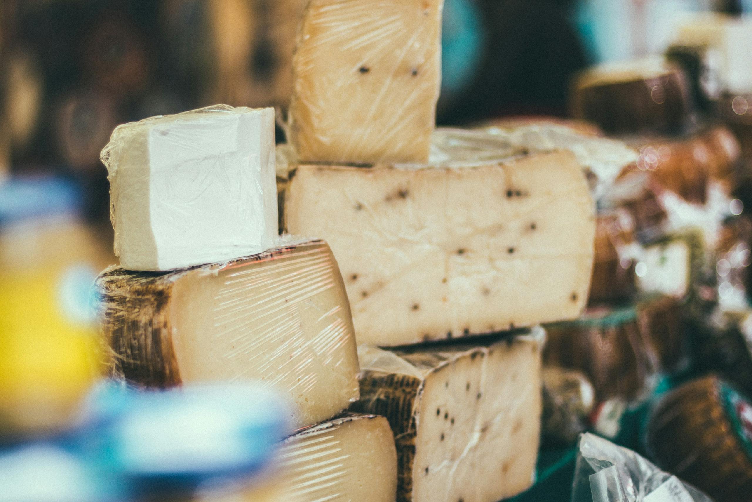 Close-up of various cheeses stacked indoors, showcasing variety and texture.