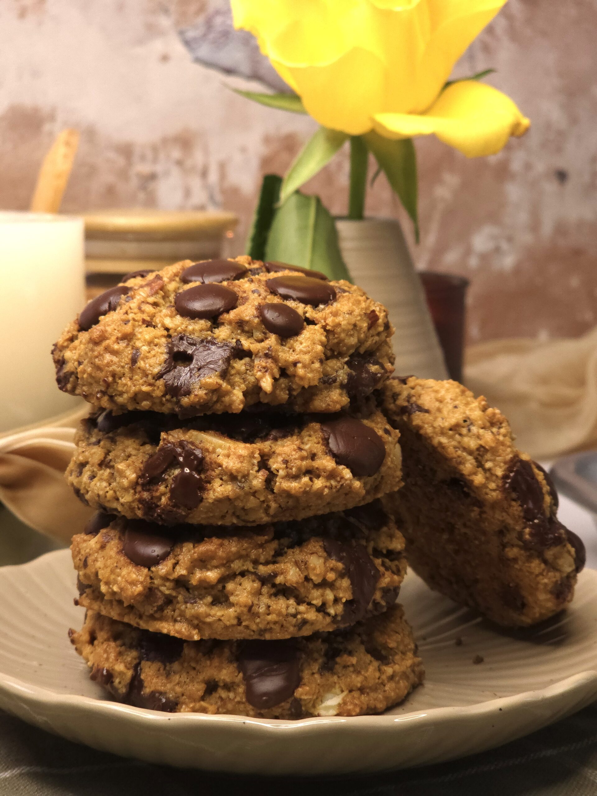 gluten-free chocolate cookies stacked on a plate next to a candle