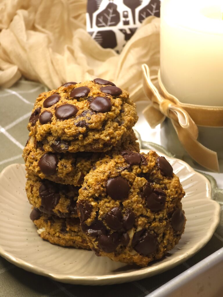 a close look of gluten-free chocolate cookies stacked on a plate next to a candle