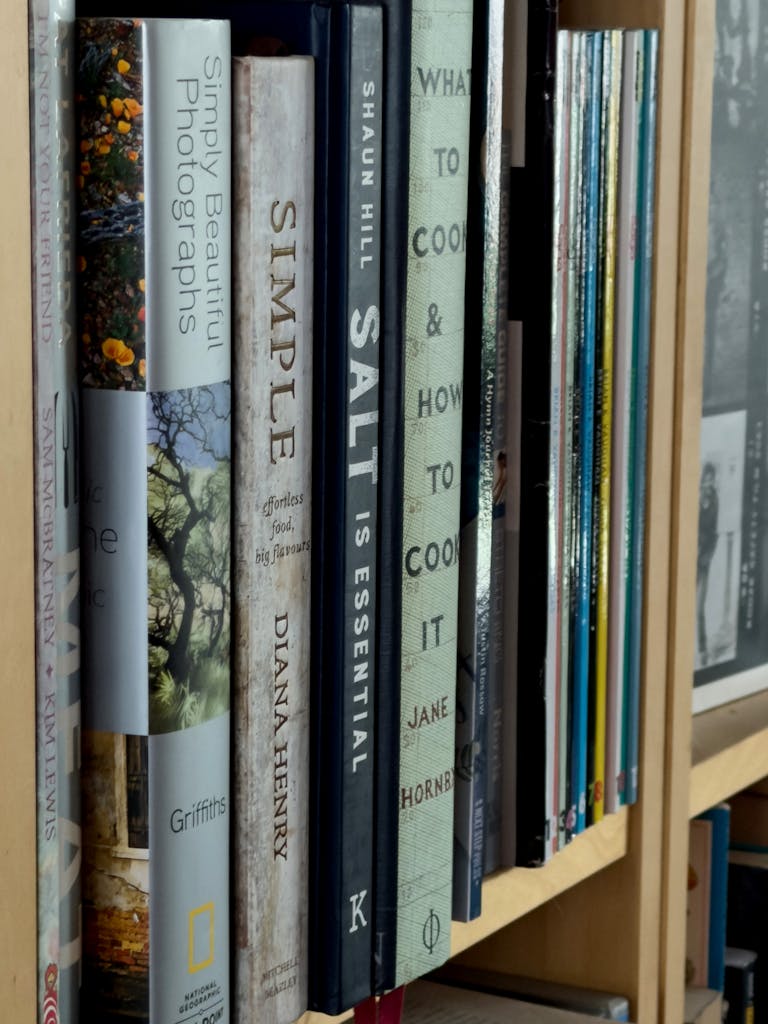 A close-up view of assorted book spines on a neatly organized wooden bookshelf.