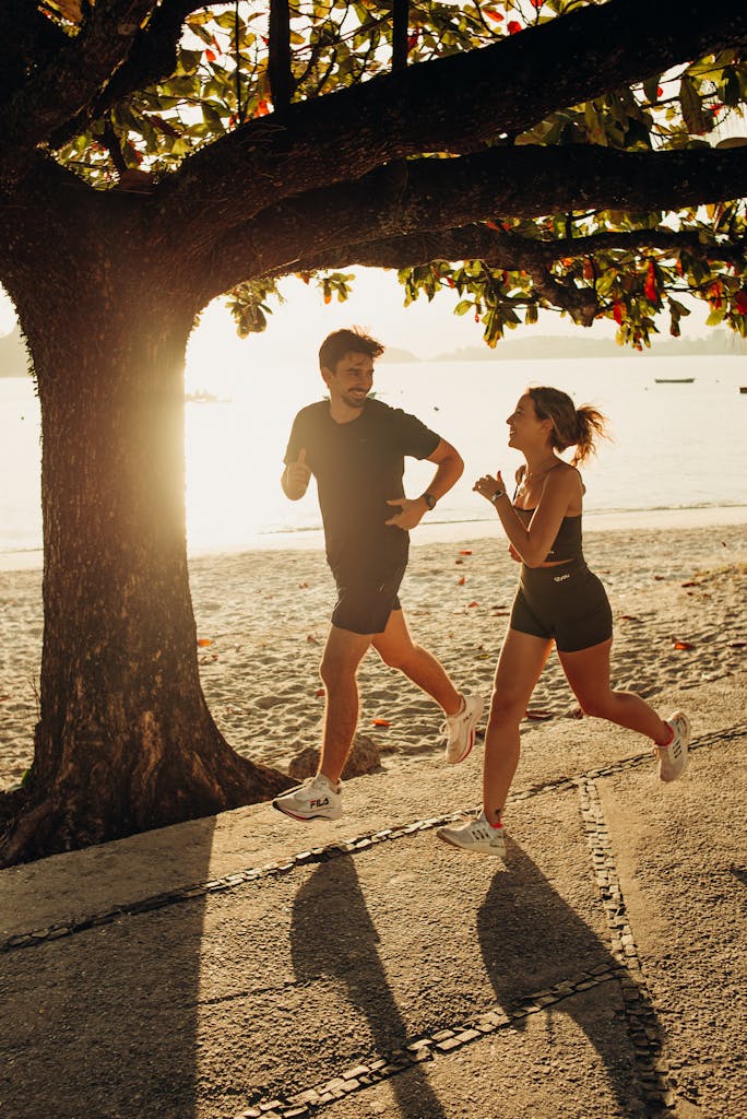 A man and woman jogging under a tree on Niterói beach at sunrise, embracing fitness and nature.
