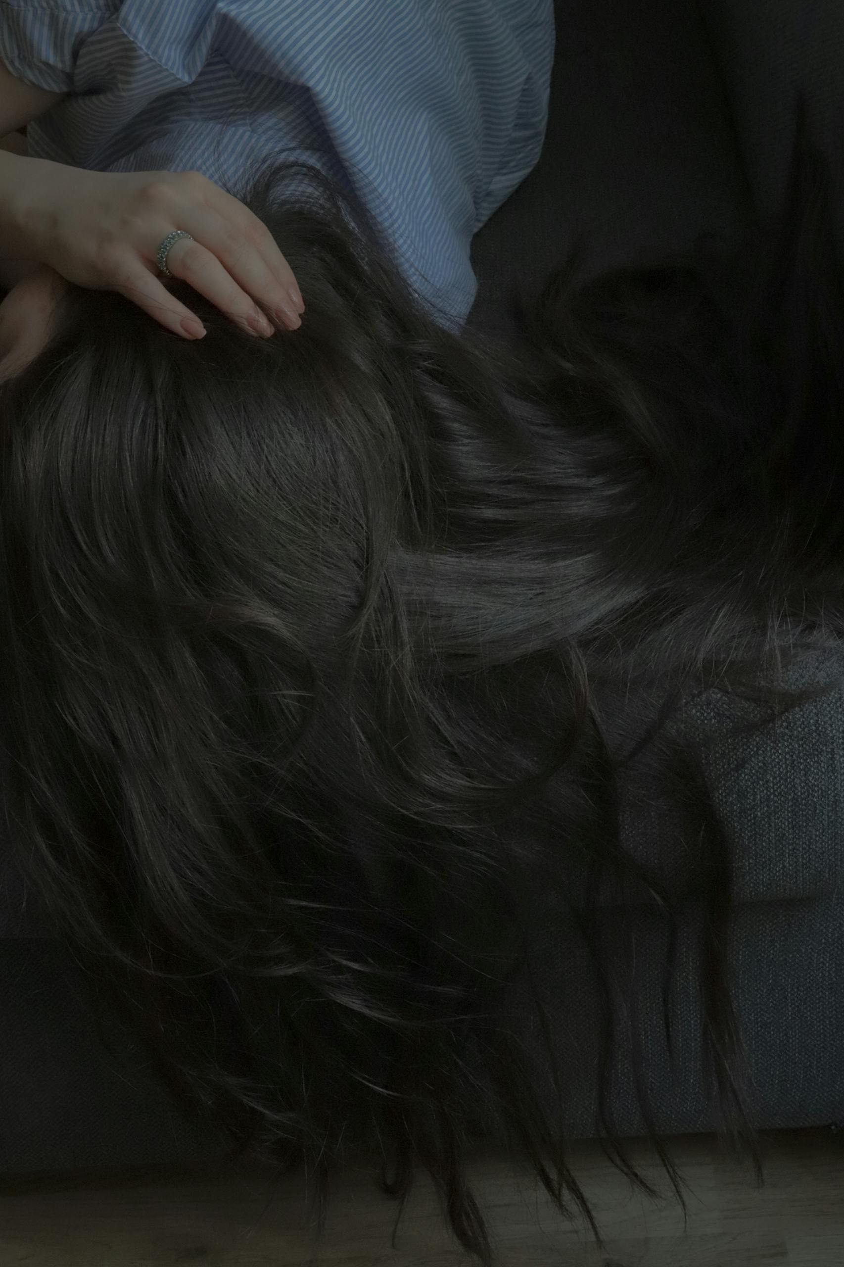 A relaxed brunette with long hair reclines on a sofa, showcasing elegance and serenity.