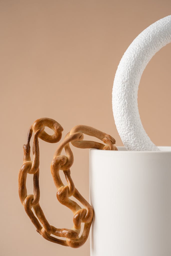 Close-up of a ceramic mug with a textured handle and a decorative chain-like element, metaphor of the wheat chain in celiac disease.