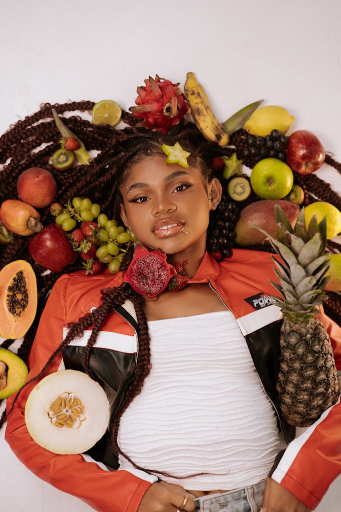 Colorful portrait of a woman surrounded by a variety of fresh fruits emphasizing natural beauty.