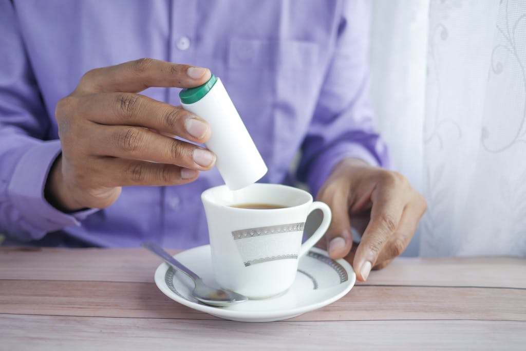Close-up of a man adding artificial sweeteners to a cup of coffee.