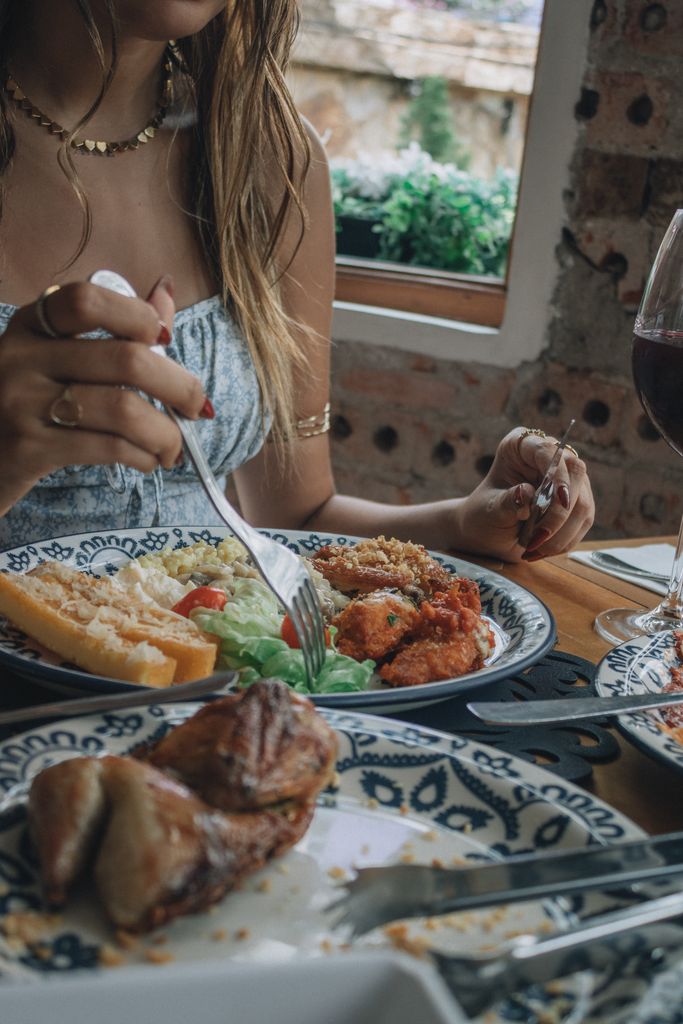 Woman dining with salad, wine, and bread in a cozy restaurant setting.