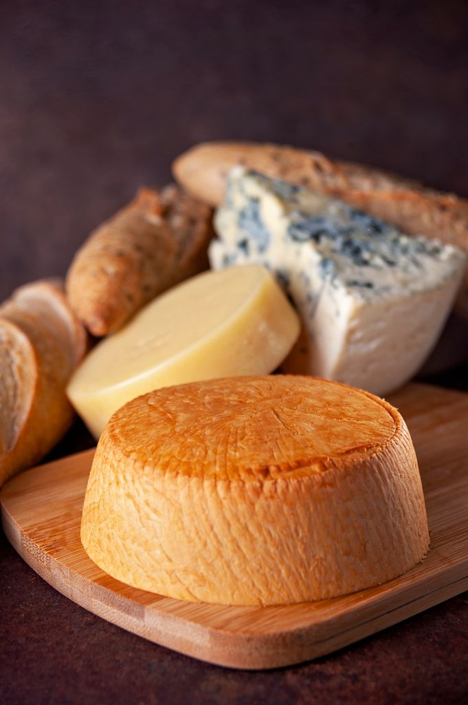 A variety of artisanal cheeses and bread displayed on a wooden board, ideal for protein speed limit explanations.