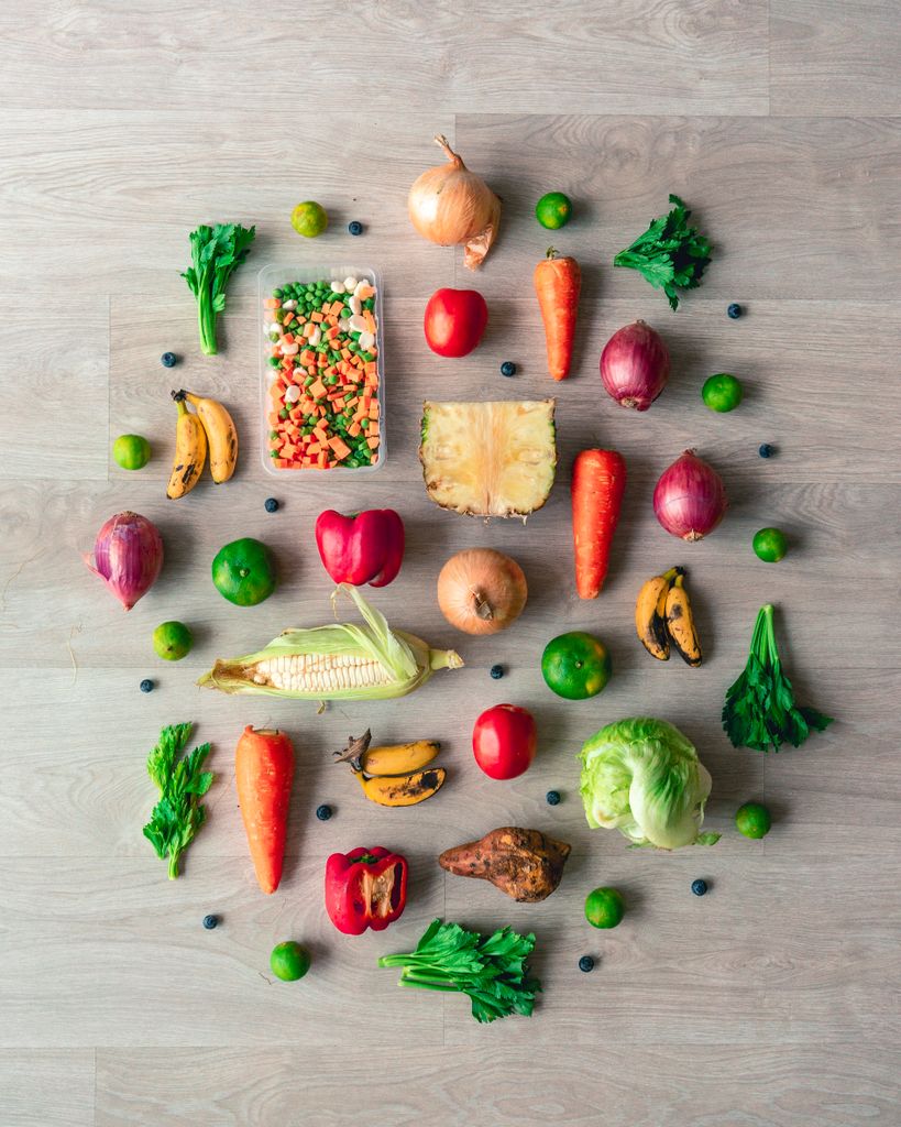Colorful flat lay featuring fresh vegetables and fruits on a wooden surface, showcasing healthy eating.