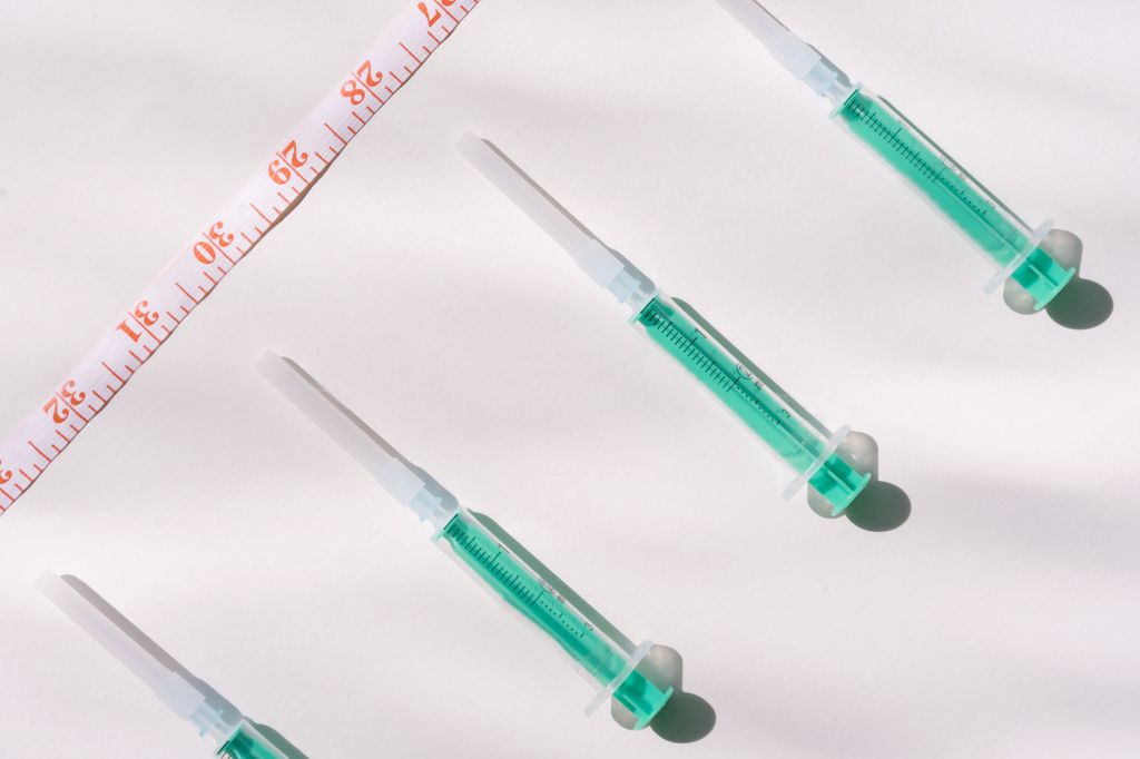 Top view of green filled syringes with weight loss peptides and measuring tape on a white background, emphasizing healthcare themes.